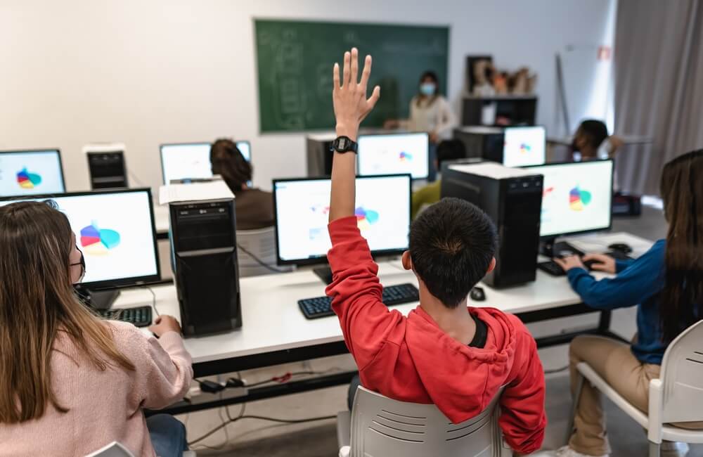 aluno levantando a mão em sala de aula para perguntar ao professor como conseguir horas complementares para faculdade